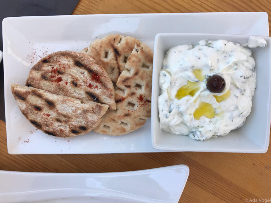 Homemade Greek Tzatziki with olive oil and an olive for decoration. Pitta bread dusted with paprika