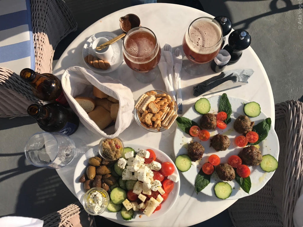 Greek plate of feta cheese, tomatoes and cucumber with meatballs, bread, crackers and beer