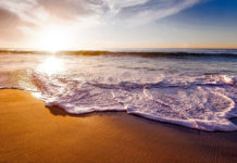 Five of the most beautiful beaches in Europe waves crashing on a beach as the sun sets on the horizon